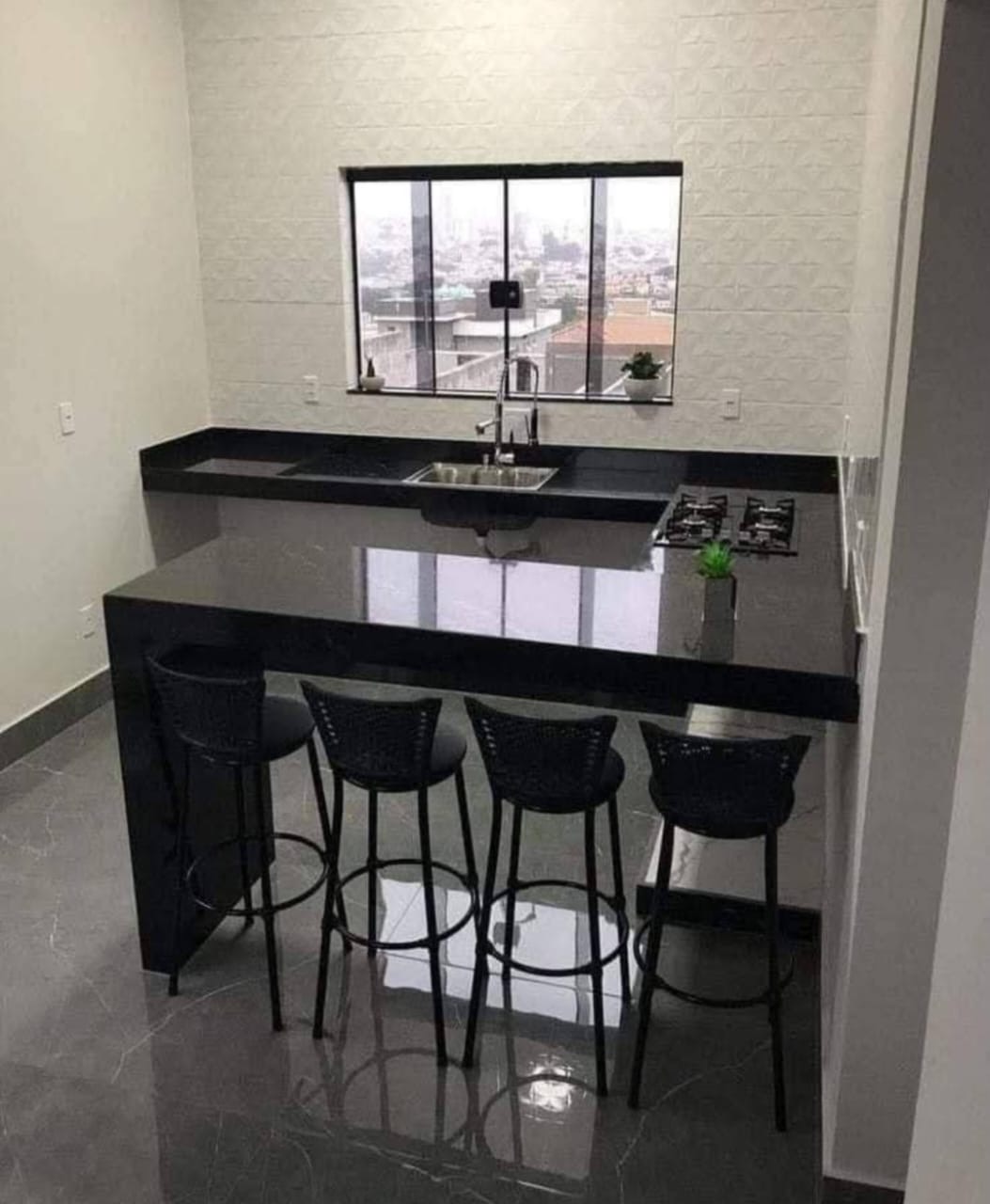 Cozinha com bancada e balcão em granito preto com banquetas