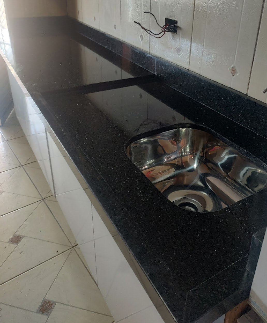 Bancada de granito preto com cuba de inox e rodabancada