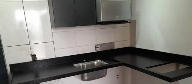 Cozinha em L com bancada de granito preto e cuba de inox