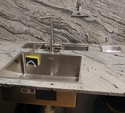 Bancada de granito claro veiado com cuba de inox e calha úmida